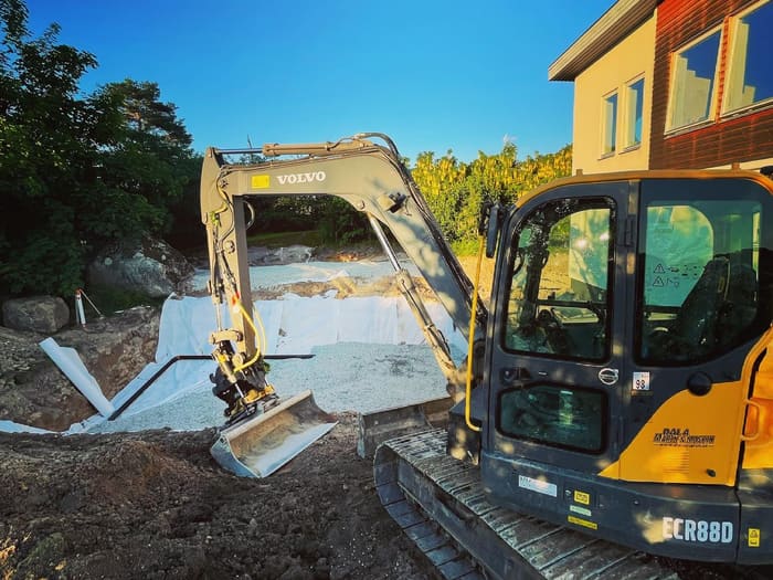 Grävmaskin schaktar för ett poolbygge vid ett bostadshus