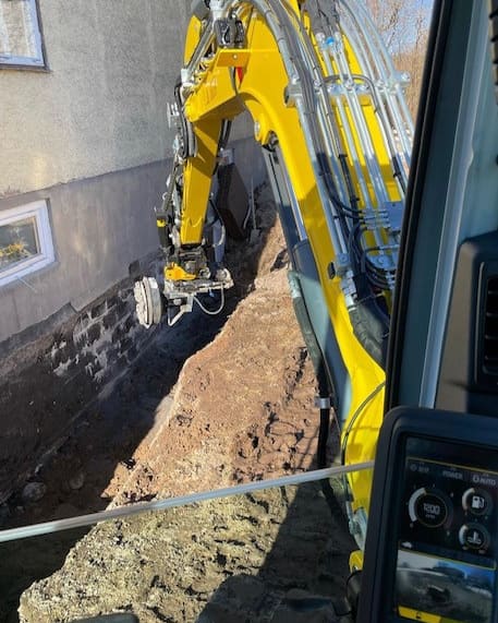 Nya dräneringsrör i en schakt längs ett hus