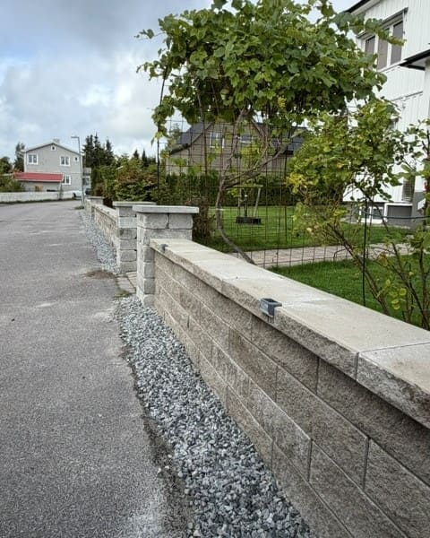 Stödmur i betongsten längs en gata med grus