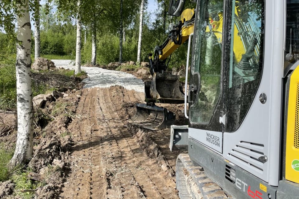Grävmaskin bygger en ny väg genom björkskog